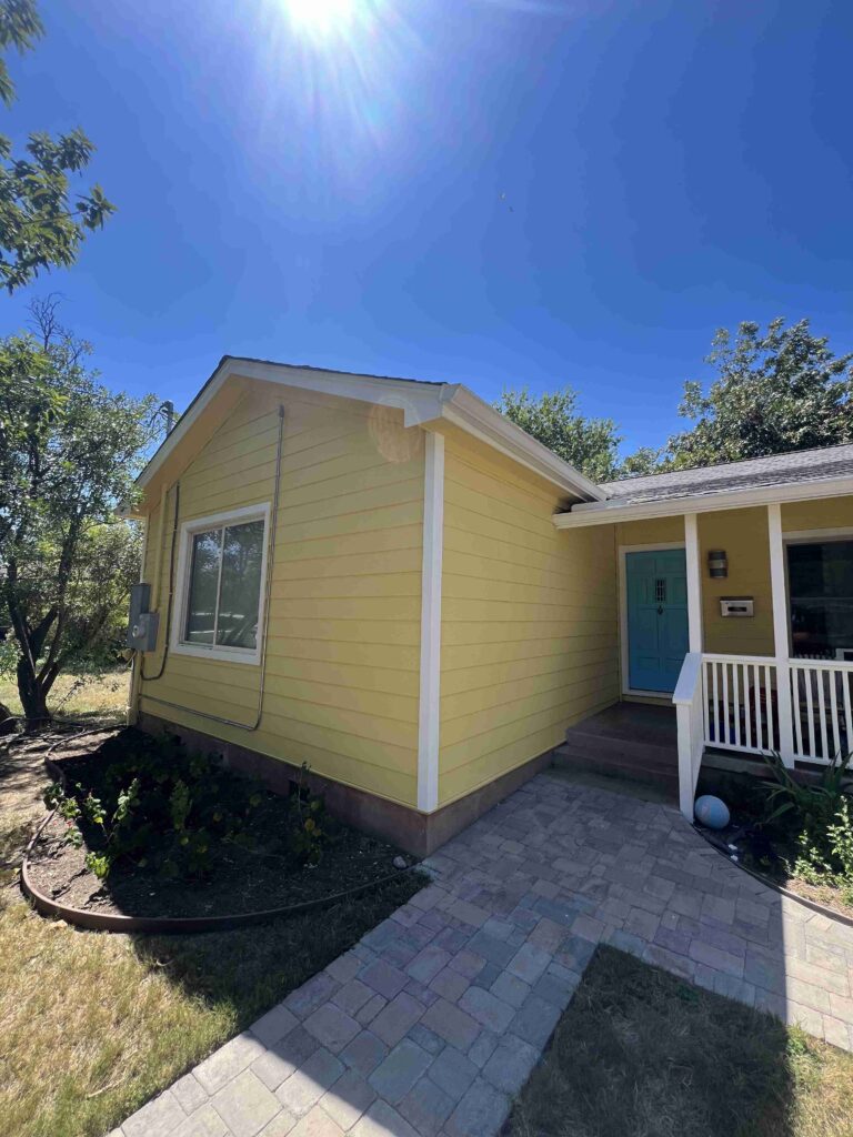 Yellow Hardie siding on a cottage with a paver walkway in Austin, TX