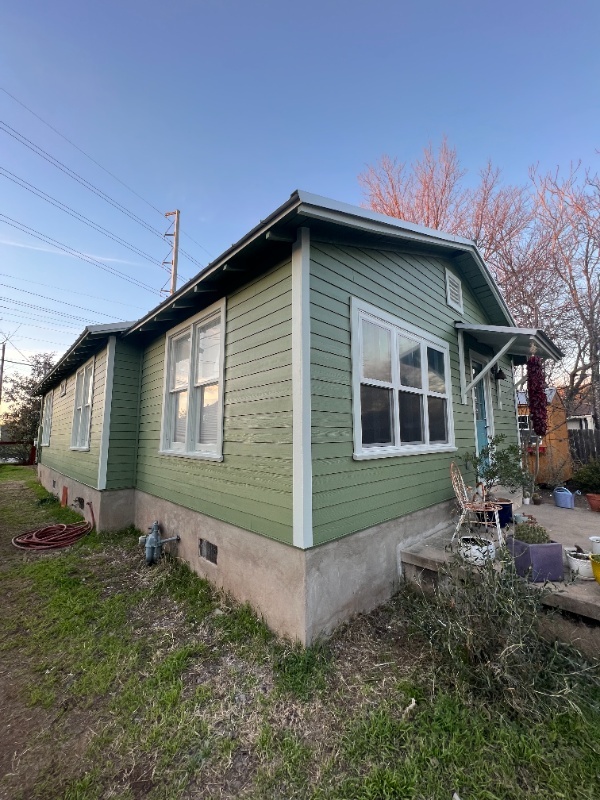 Green Hardie lap siding on a bungalow with white windows in Austin, TX