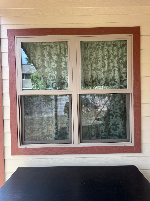 Double-hung windows with red trim on cream siding in Austin, TX