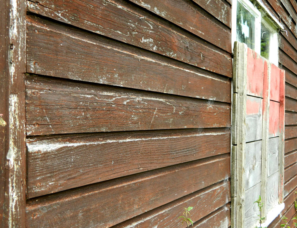 Weathered wood siding showing peeling paint and moisture wear representing environmental siding damage in Austin TX