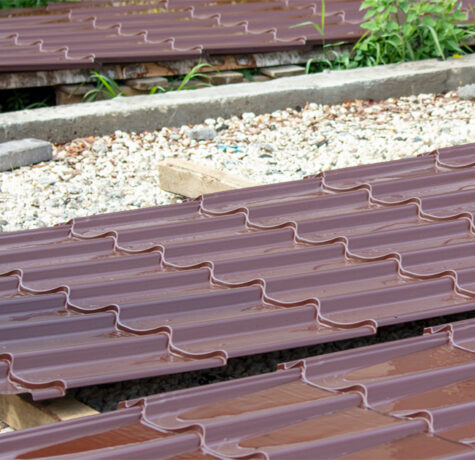 Metal roofing installation process showing roofing panels being secured to roof decking