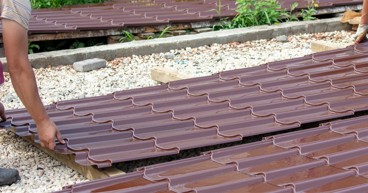Metal roofing installation process showing roofing panels being secured to roof decking