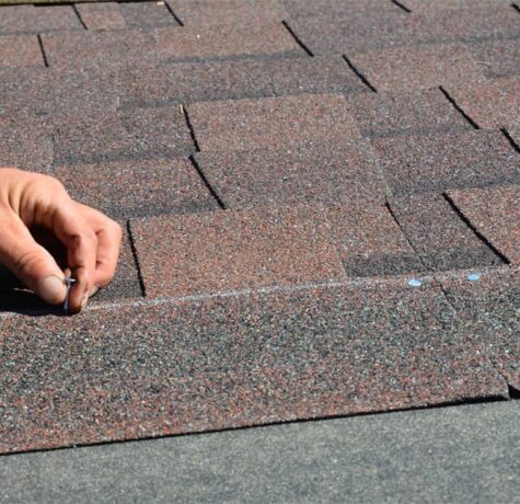 Roof replacement installation process showing new shingles being installed