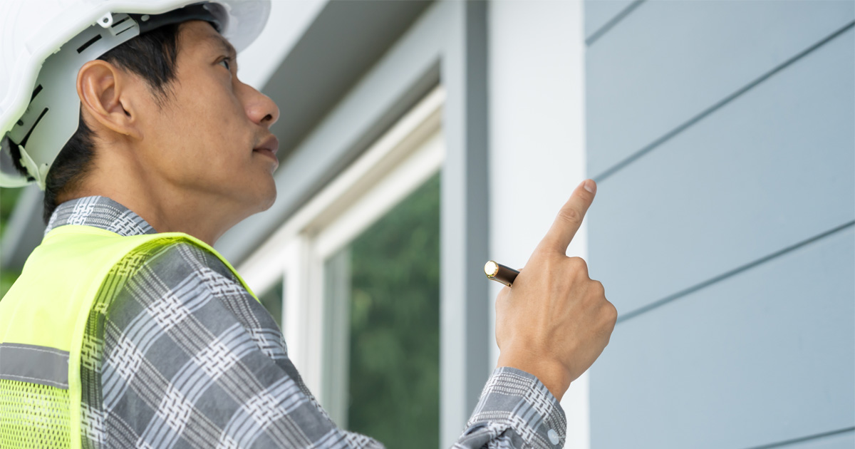 Professional shingle siding contractor inspecting newly installed exterior shingles