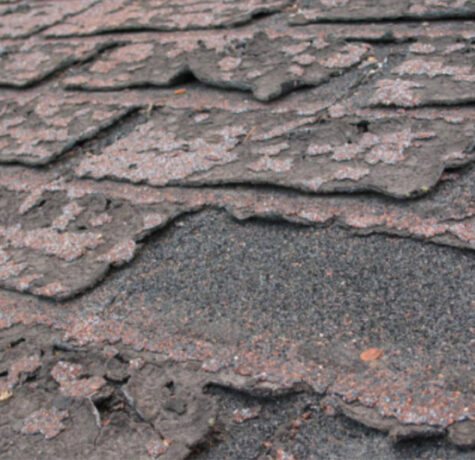 Asphalt shingle roofing with visible curling and cracked shingles caused by heat exposure and aging materials
