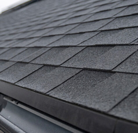 Close-up of dark asphalt shingles and a gutter edge on a residential roof