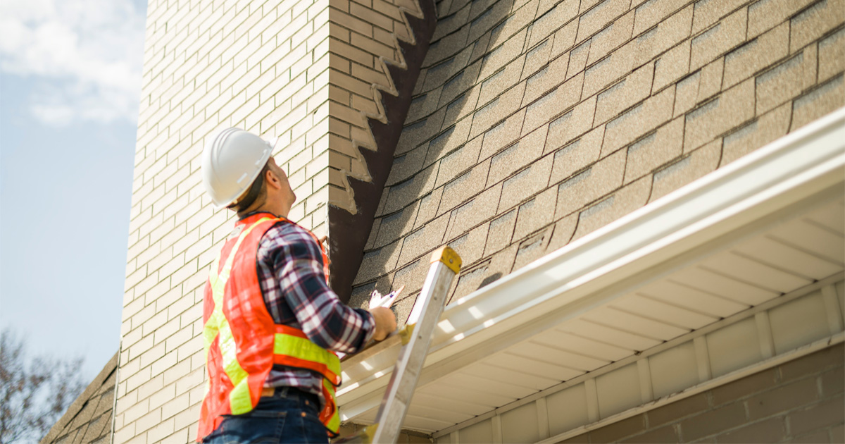 Roofing contractor on a ladder inspecting a roofline for hidden leaks on an Austin, TX home