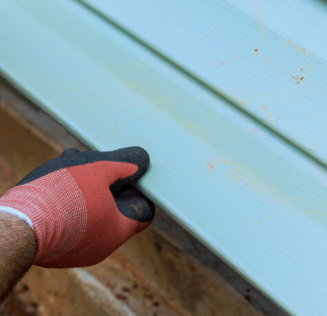 Installer fitting a new light blue vinyl siding panel on an Austin, TX home