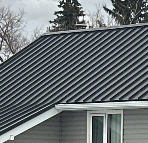 Dark standing seam metal roof panels on a gray two-story home in Austin, TX