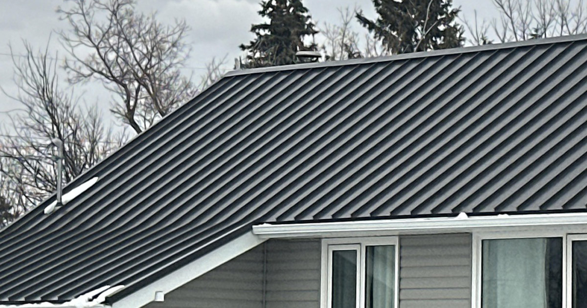 Dark standing seam metal roof panels on a gray two-story home in Austin, TX