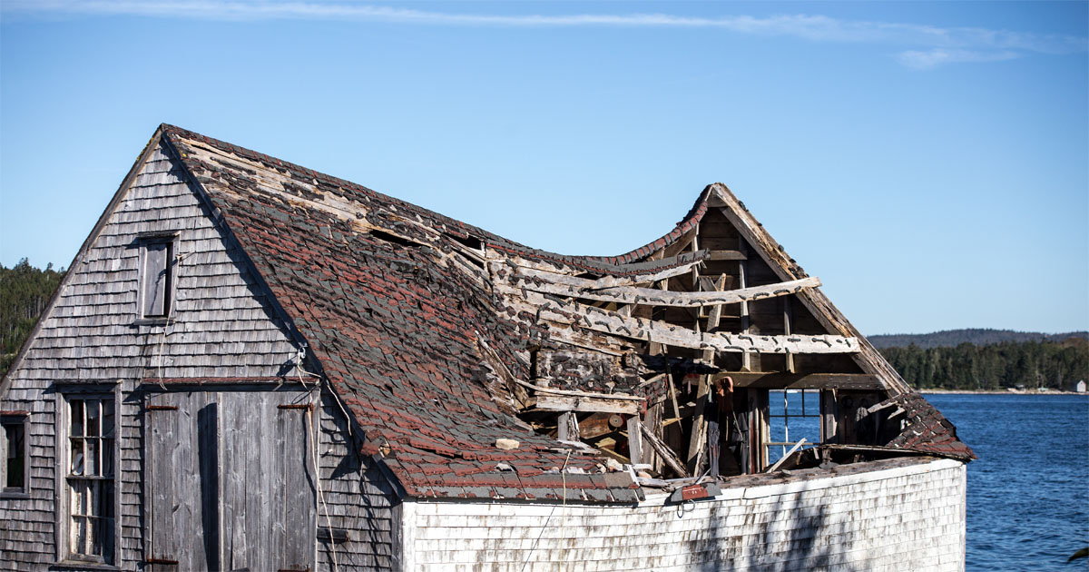 Old wooden house with a sagging, collapsing roof structure