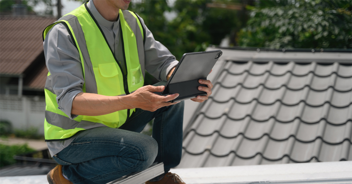 Roofing inspector with a tablet checking a metal tile roof in Hutto, TX, near Austin