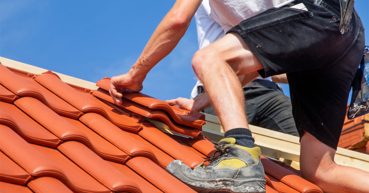 Roofer installing red clay tile roofing on a home in Manor, TX, near Austin
