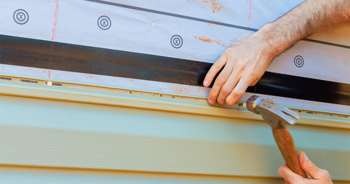 Installer nailing new vinyl siding panels on a home in Hutto, TX, near Austin