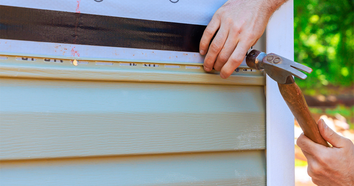 Contractor hammering vinyl siding into place on a home in Manor, TX, near Austin