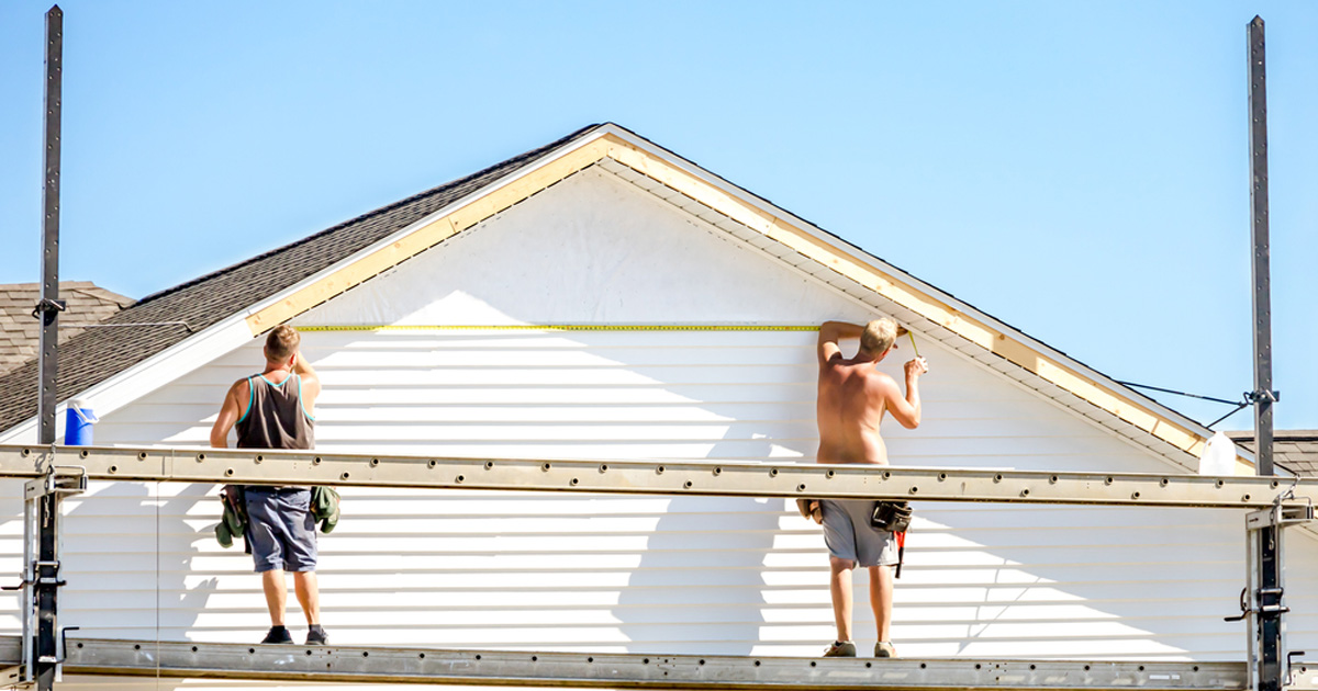 Installers on scaffolding putting up white lap siding on a home gable in Austin, TX