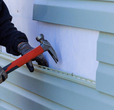 Installer hammering a new light blue siding panel into place during a siding repair in Austin, TX